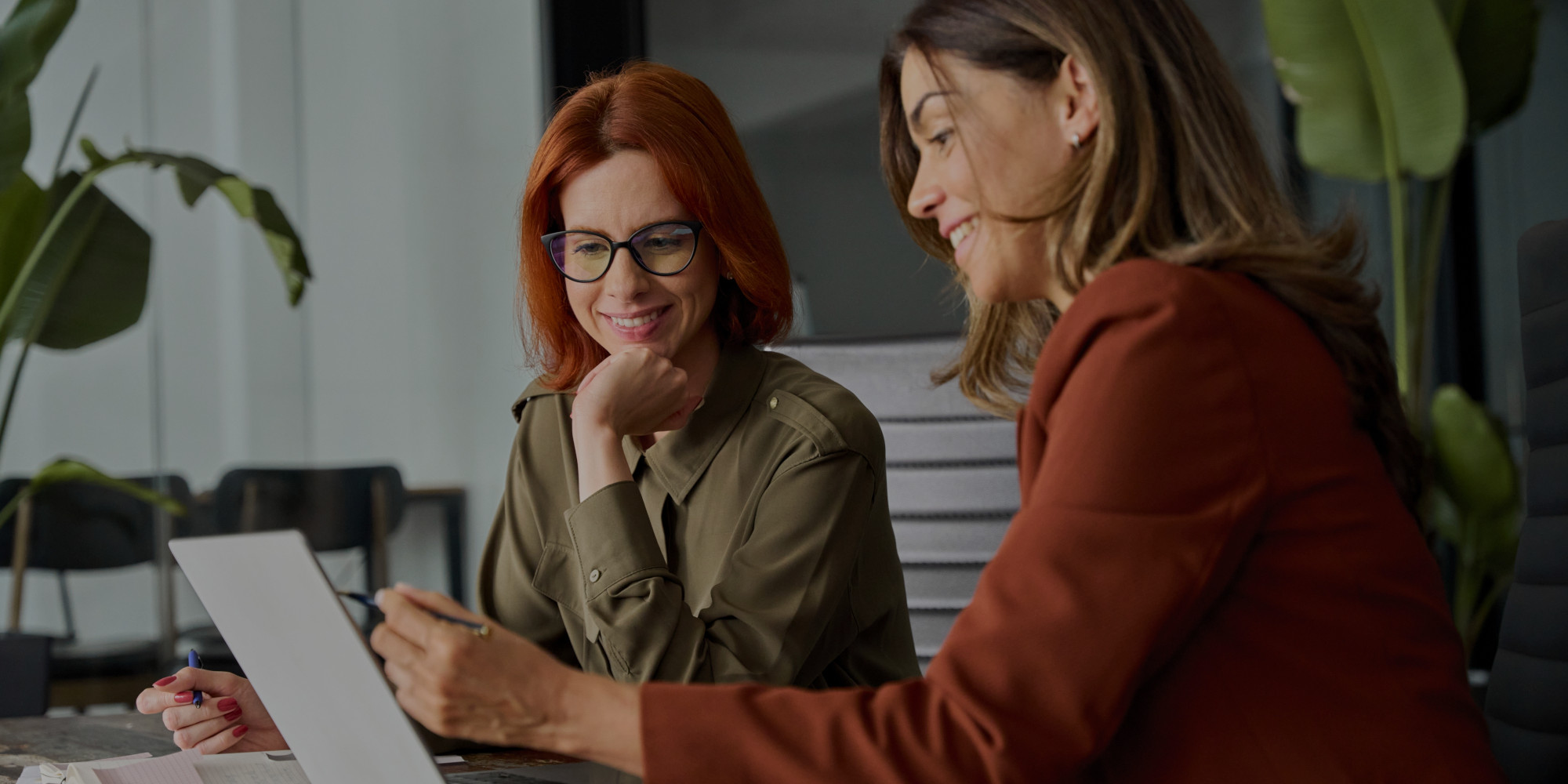 imagen de dos mujeres charlando distendidamente en un entorno de trabajo mientras miran una pantalla de ordenador