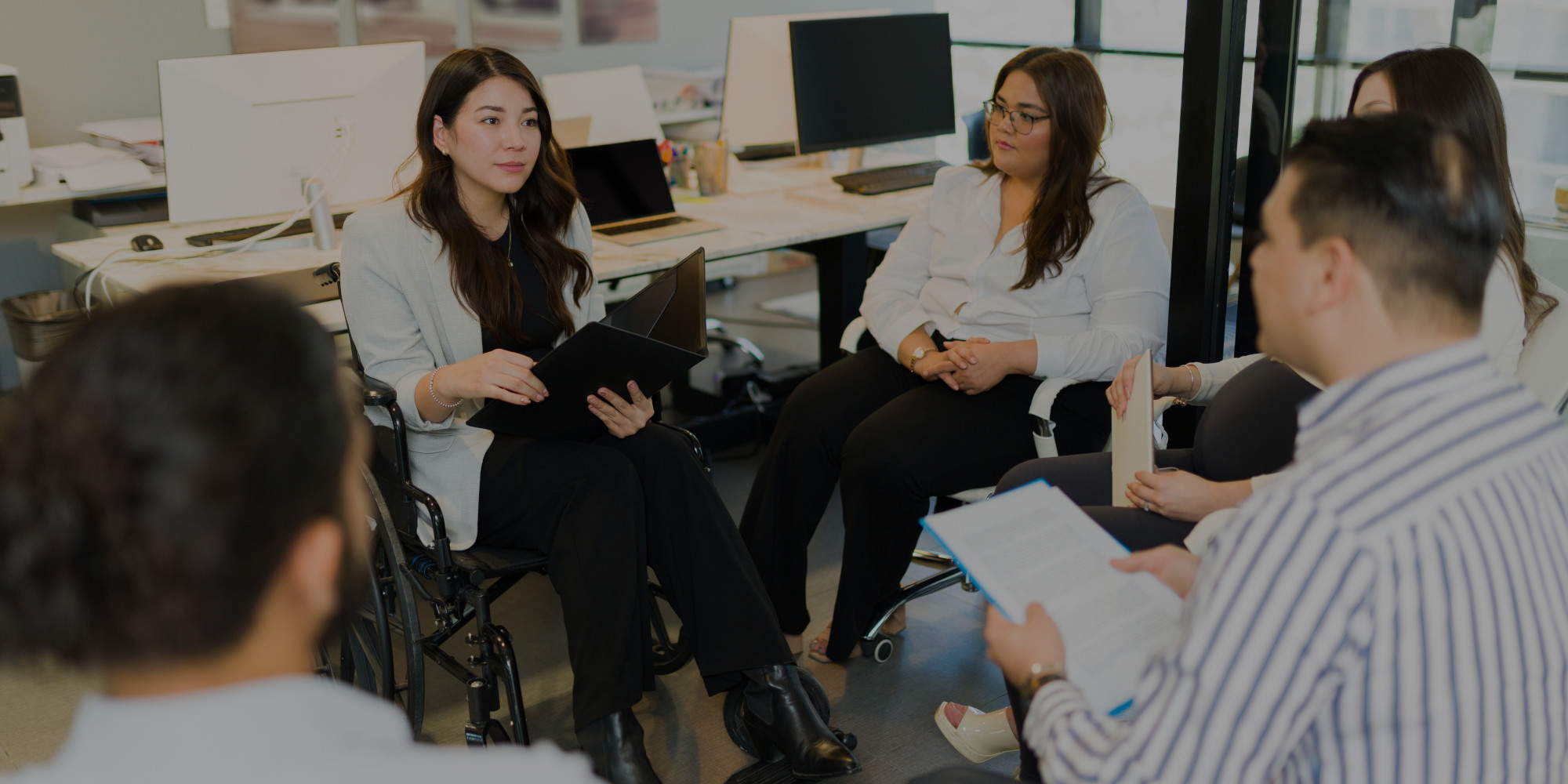 imagen de un grupo de personas reunidas a modo de trabajo, una de ellas está sentada en una silla de ruedas